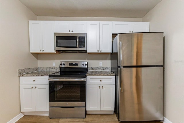 kitchen featuring baseboards, appliances with stainless steel finishes, light wood-style flooring, and white cabinets