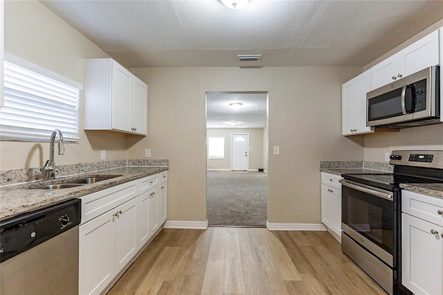 kitchen featuring a sink, visible vents, white cabinets, light wood-style floors, and appliances with stainless steel finishes