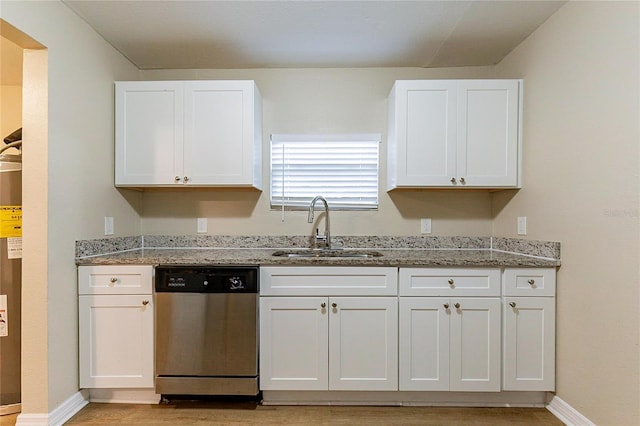 kitchen with light stone counters, white cabinetry, dishwasher, and a sink