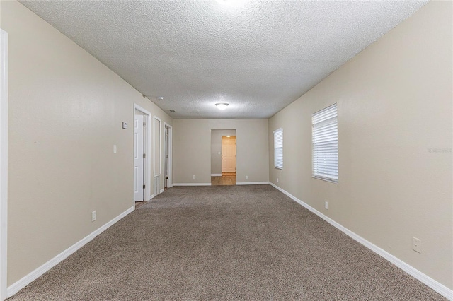 carpeted empty room featuring baseboards and a textured ceiling