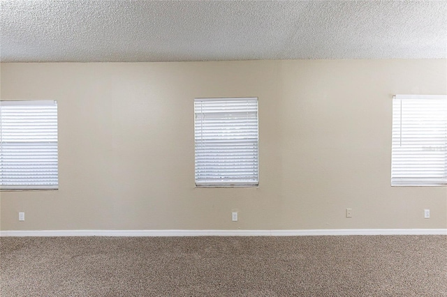 empty room featuring carpet flooring, a textured ceiling, and baseboards