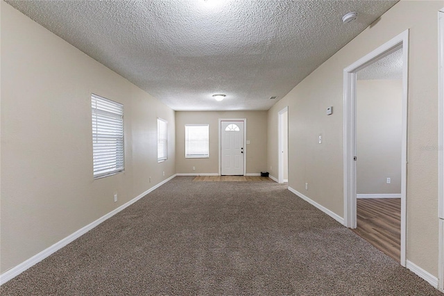 foyer with carpet, a textured ceiling, and baseboards