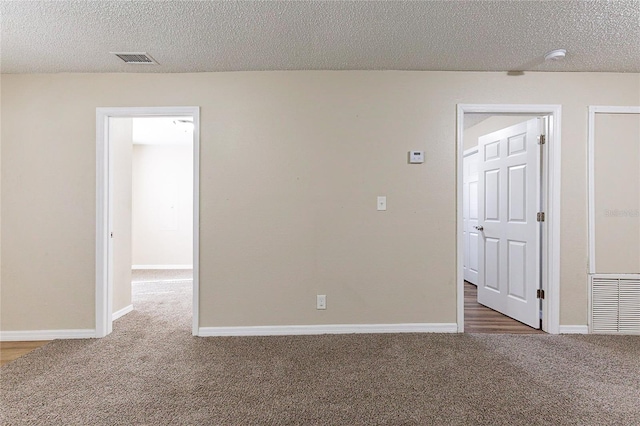 carpeted spare room featuring baseboards, visible vents, and a textured ceiling