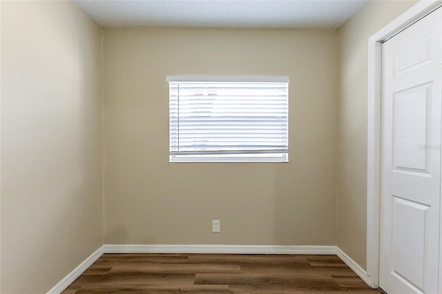 empty room featuring baseboards and dark wood-style flooring