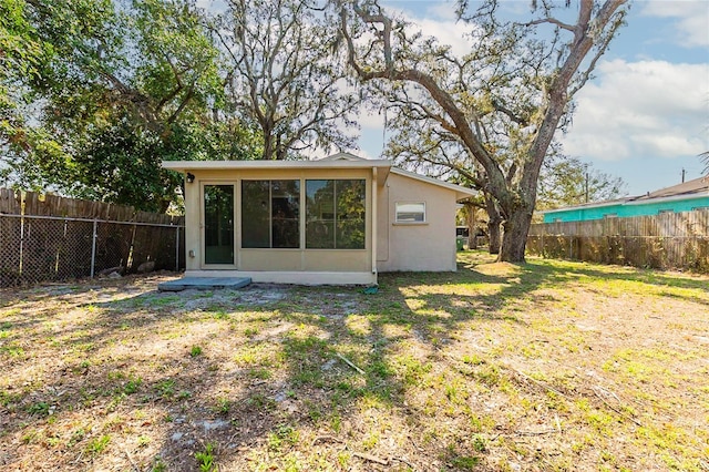 rear view of house featuring a fenced backyard, a lawn, and stucco siding