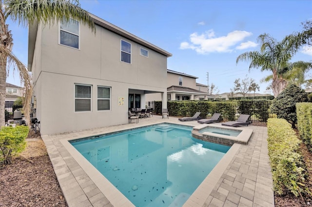 back of property featuring a patio area, a pool with connected hot tub, fence, and stucco siding