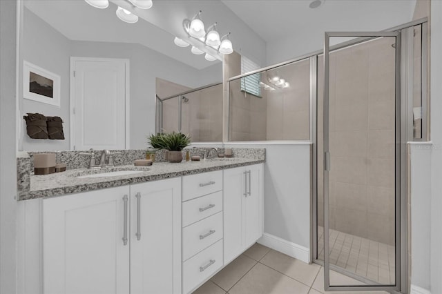 full bathroom with double vanity, a stall shower, a sink, and tile patterned floors