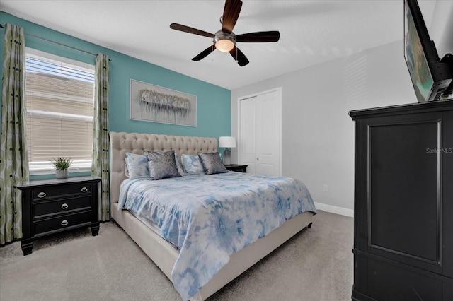 bedroom featuring a ceiling fan, a closet, light carpet, and baseboards