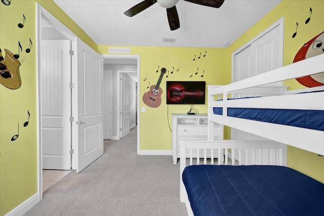 bedroom featuring baseboards, light colored carpet, visible vents, and a textured ceiling