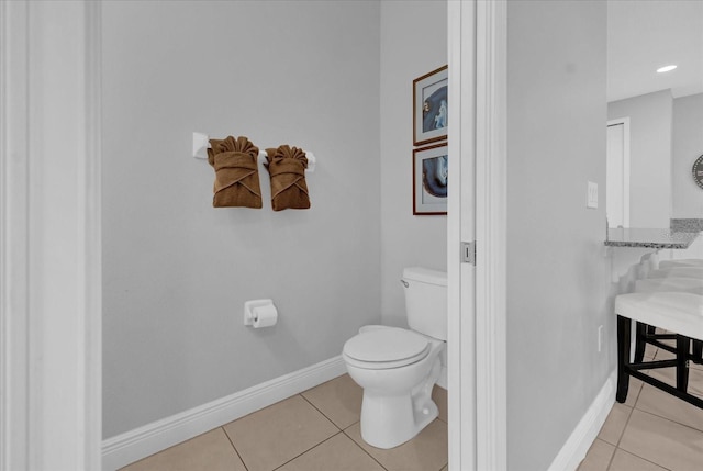 bathroom featuring baseboards, tile patterned floors, and toilet