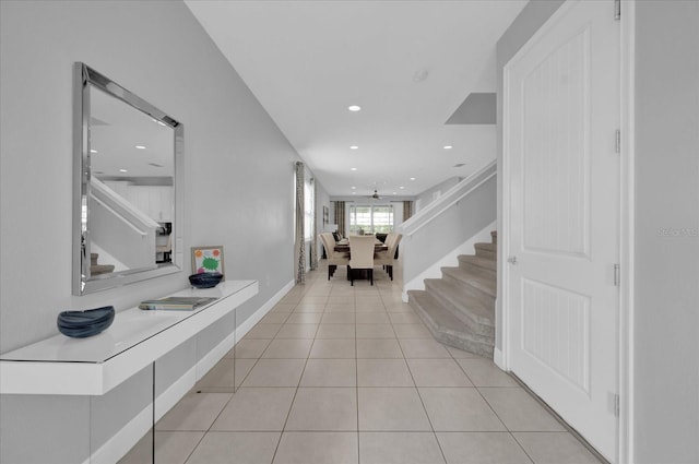 corridor with light tile patterned flooring, recessed lighting, and stairway