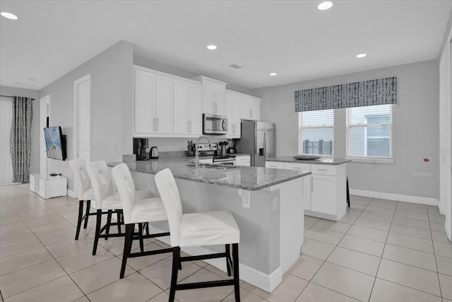 kitchen featuring stainless steel appliances, light stone countertops, light tile patterned floors, and a peninsula