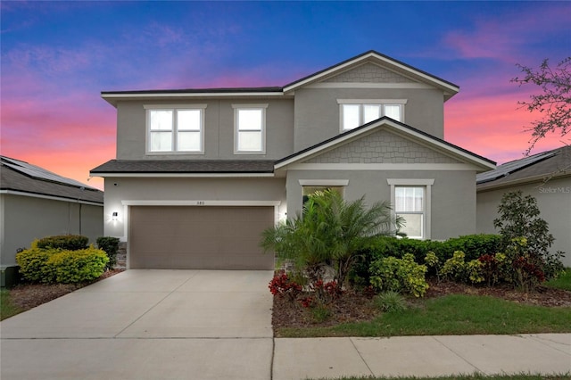 traditional-style house with a garage, concrete driveway, and stucco siding