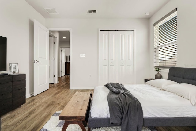 bedroom featuring a closet, baseboards, visible vents, and light wood finished floors