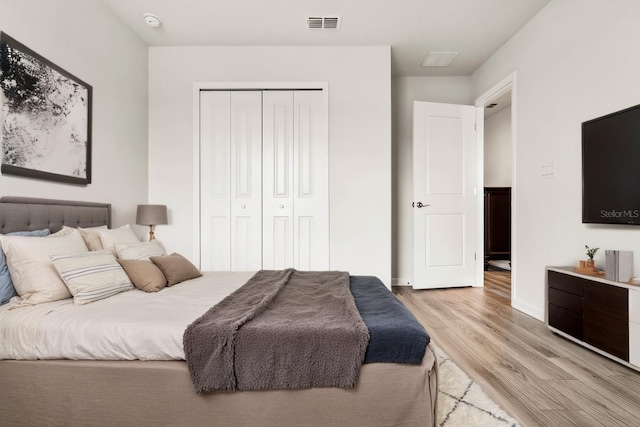 bedroom with baseboards, a closet, visible vents, and light wood-style floors