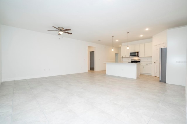 kitchen with appliances with stainless steel finishes, decorative light fixtures, ceiling fan, a kitchen island, and white cabinetry