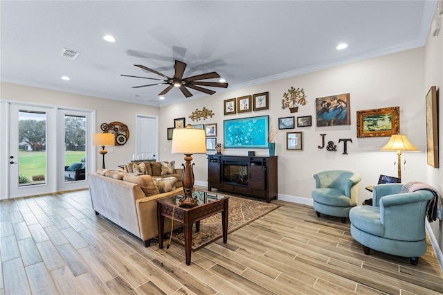 living area featuring wood finish floors, crown molding, and ceiling fan