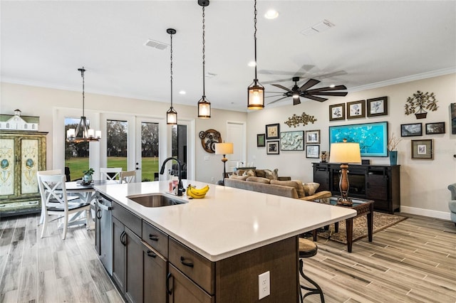 kitchen featuring light countertops, hanging light fixtures, visible vents, a sink, and dark brown cabinetry