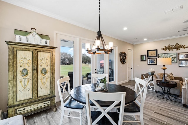 dining room with a chandelier, wood finish floors, visible vents, and crown molding