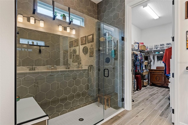 full bathroom featuring a shower stall, a walk in closet, and wood finish floors