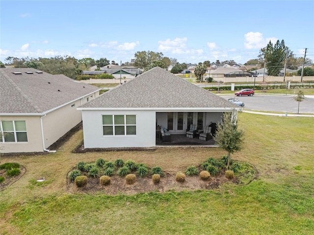 rear view of property featuring a yard, roof with shingles, a residential view, and stucco siding