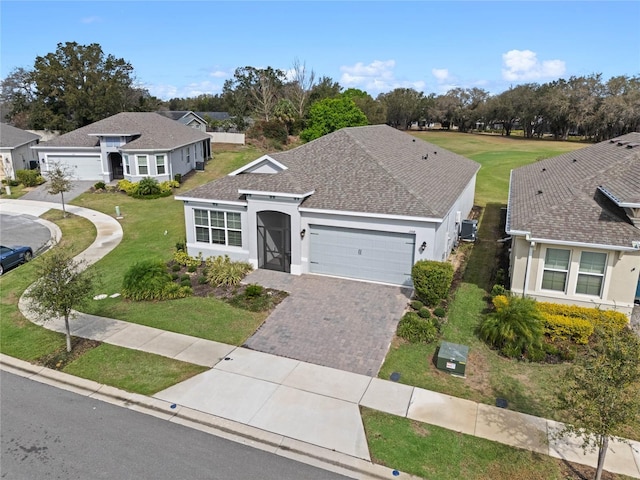 view of front facade with a garage, a shingled roof, decorative driveway, and stucco siding