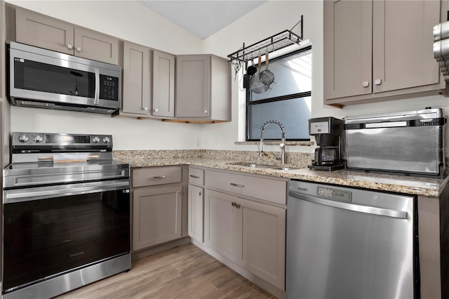 2531 Ludlow St, Deltona, FL 32738 - kitchen featuring light wood-style flooring, vaulted ceiling, appliances with stainless steel finishes, a sink, and gray cabinetry