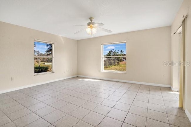 spare room featuring plenty of natural light, baseboards, a ceiling fan, and light tile patterned floors