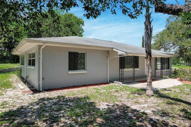 view of front of house featuring concrete block siding and a patio