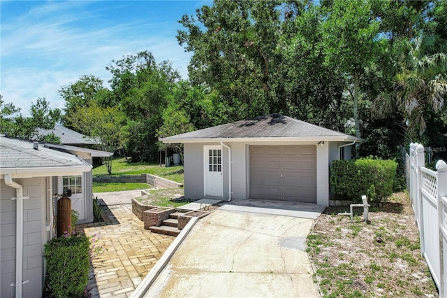 detached garage featuring fence and concrete driveway