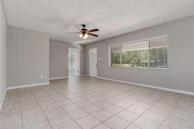 empty room with baseboards, ceiling fan, and a textured ceiling