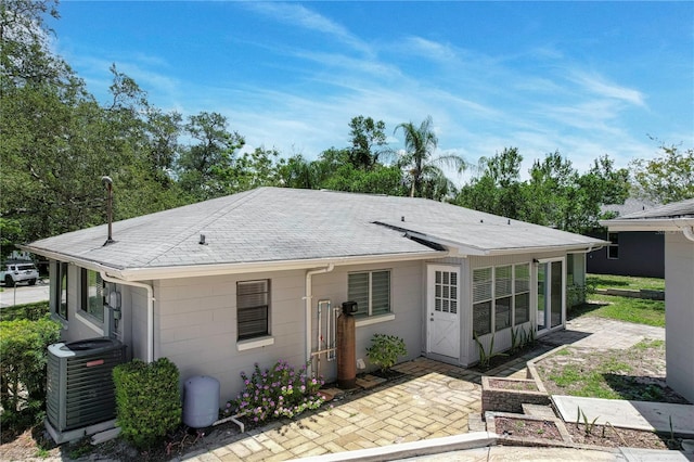 rear view of property with central AC unit and a shingled roof