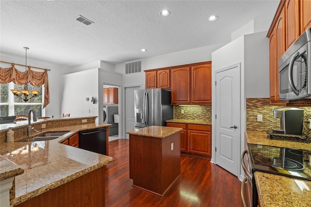 kitchen with a sink, stainless steel appliances, visible vents, and a center island with sink