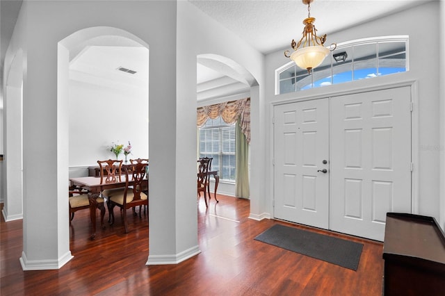 foyer with visible vents, baseboards, arched walkways, dark wood-style flooring, and a textured ceiling