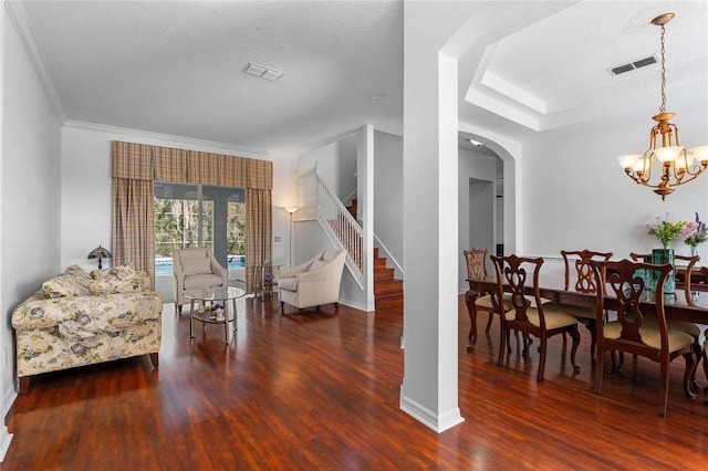 dining area featuring visible vents, a chandelier, stairway, wood finished floors, and arched walkways