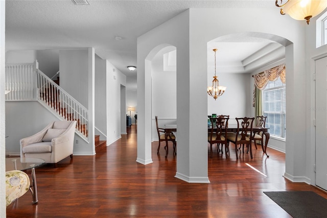 interior space featuring stairs, an inviting chandelier, wood finished floors, and arched walkways