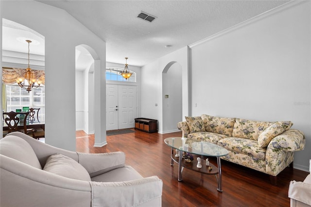 living room featuring a wealth of natural light, arched walkways, a chandelier, and wood finished floors