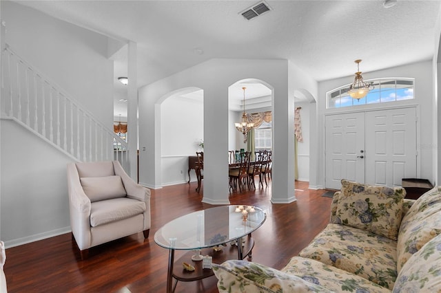 living room with visible vents, arched walkways, an inviting chandelier, and wood finished floors