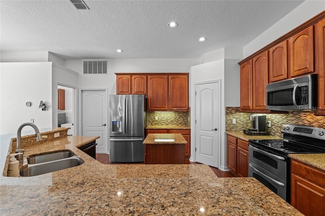 kitchen with visible vents, light stone counters, decorative backsplash, stainless steel appliances, and a sink