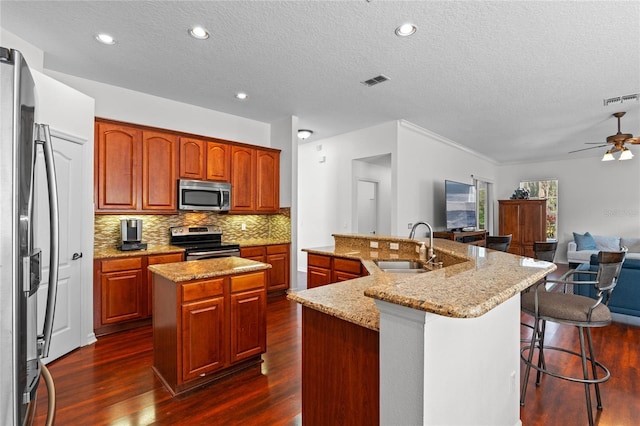 kitchen featuring a sink, visible vents, a large island with sink, and stainless steel appliances