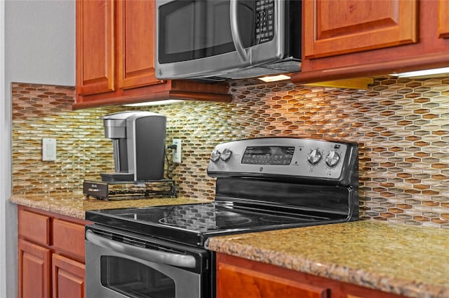 kitchen featuring backsplash, appliances with stainless steel finishes, and light stone countertops