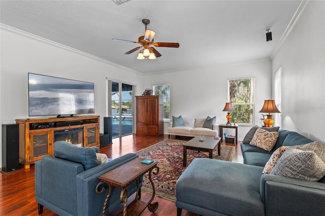 living area featuring a glass covered fireplace, crown molding, ceiling fan, and wood finished floors