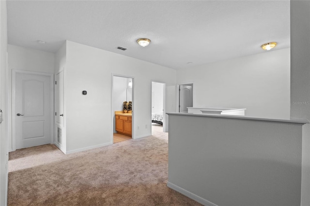 empty room featuring visible vents, light colored carpet, and baseboards