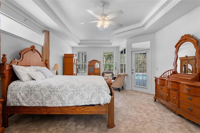 bedroom with light colored carpet, a raised ceiling, a ceiling fan, and access to outside