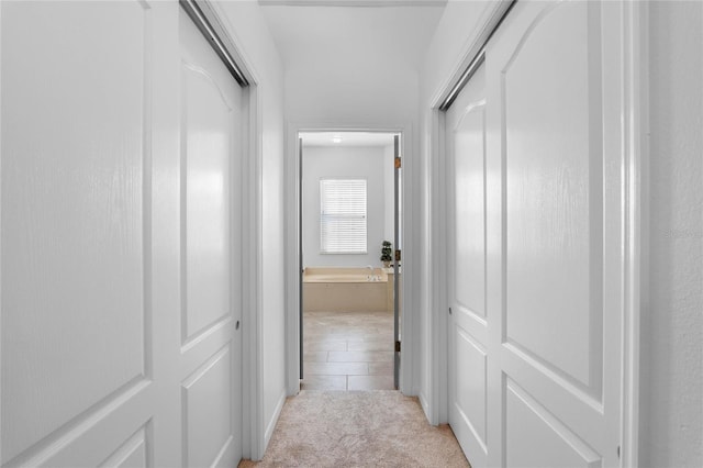 corridor featuring light colored carpet