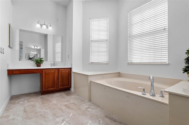 bathroom featuring a wealth of natural light, baseboards, vanity, and a garden tub