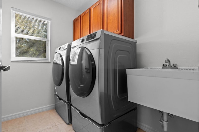 clothes washing area featuring washer and dryer, baseboards, cabinet space, and light tile patterned floors