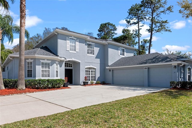 view of front facade with stucco siding, driveway, a front lawn, and an attached garage