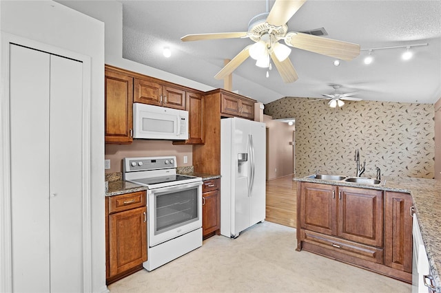 kitchen with a sink, brown cabinets, white appliances, lofted ceiling, and light stone countertops