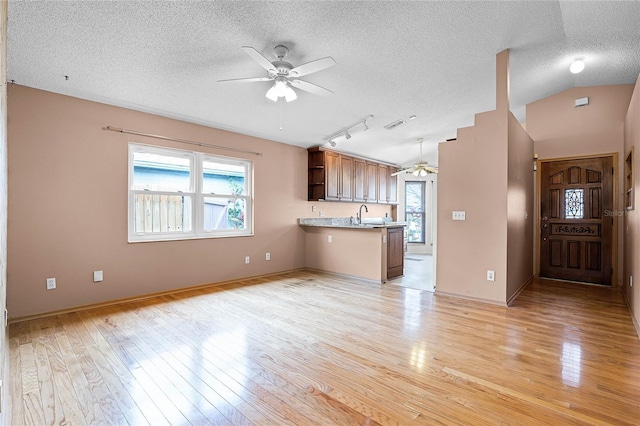 kitchen with open floor plan, brown cabinets, light countertops, open shelves, and a peninsula